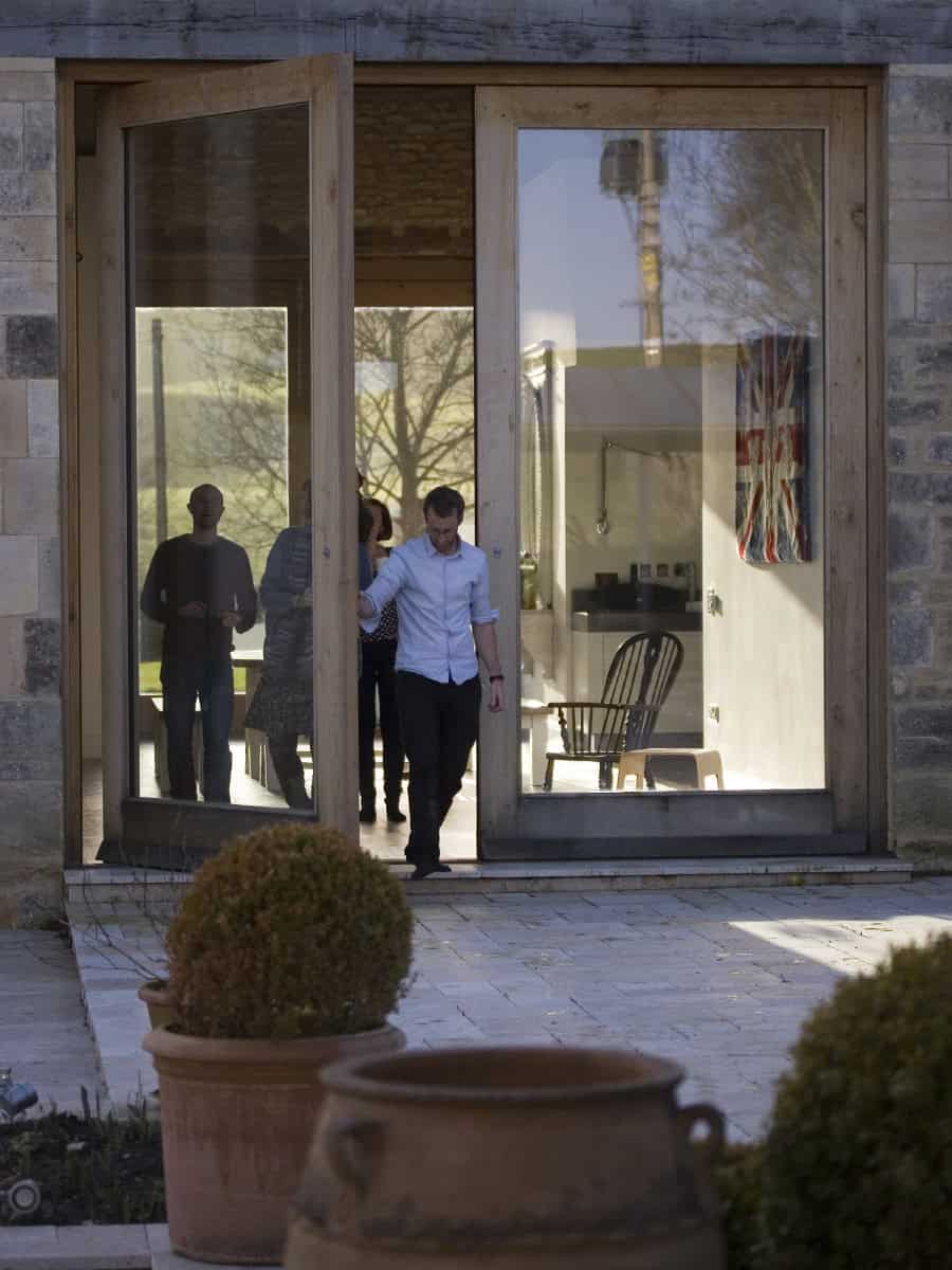 People stepping through full-height oak-framed glazed doors at Vale Farm barn conversion